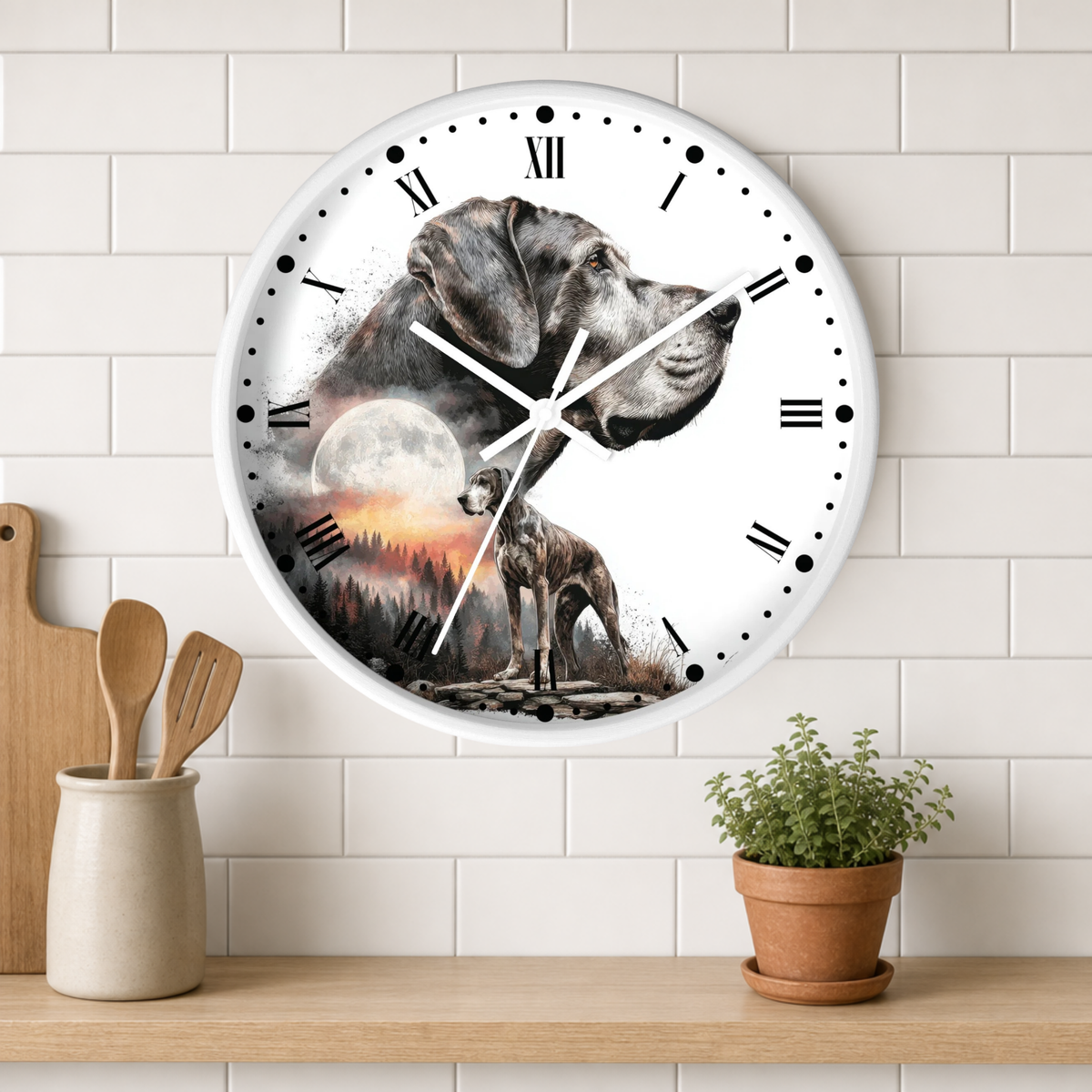 A round wall clock with a white face and black Roman numerals, featuring a printed design of a gray dog and a deer in front of a moonlit landscape. The clock is mounted on a white subway tile wall above a wooden shelf with a small potted plant and wooden utensils.