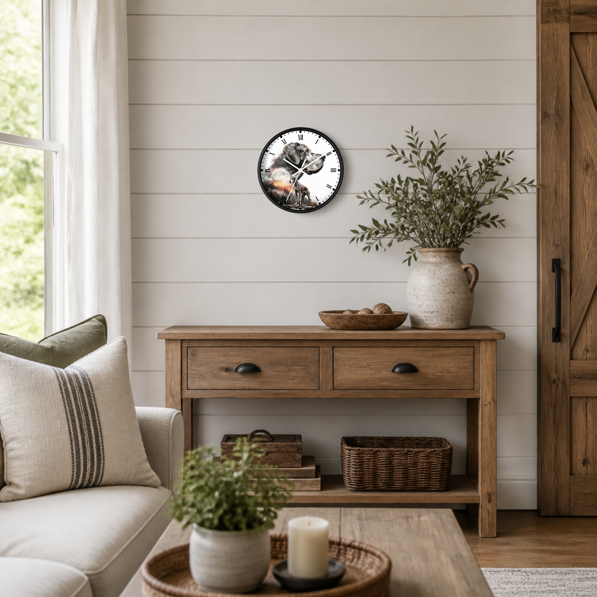 A round wall clock with a black frame and a great Dane dog graphic, styled on a white shiplap wall above a rustic wooden console table in a bright, modern farmhouse living room.