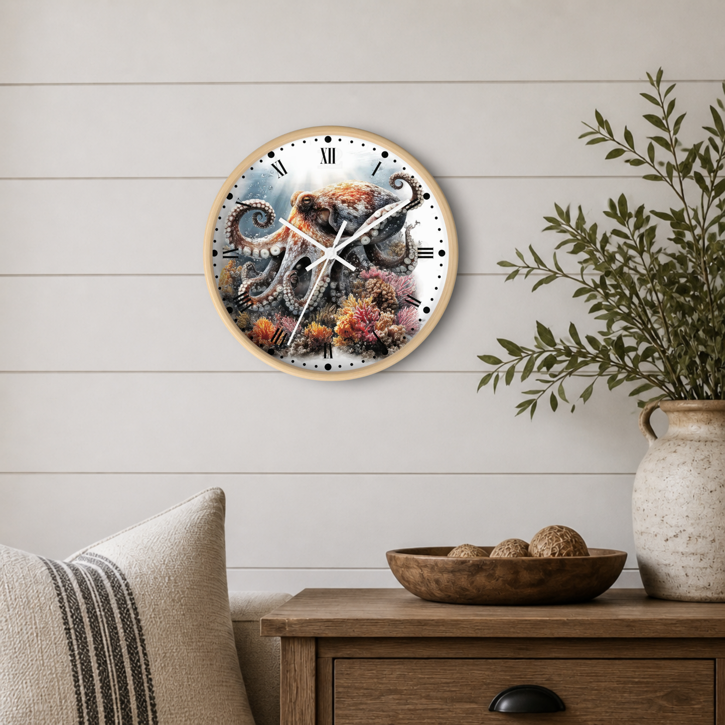 A round wall clock with a natural wood frame hangs on a white shiplap wall above a wooden side table. The clock face features a detailed illustration of an octopus among colorful coral reefs.
