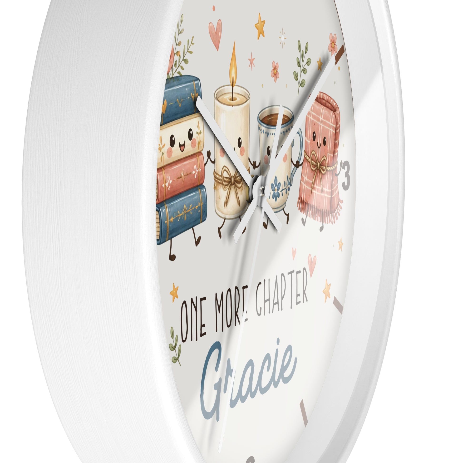 A round white wall clock with a whimsical illustration of books, a candle, a mug, and a scarf on the face, plus the text 'ONE MORE CHAPTER Gracie'.