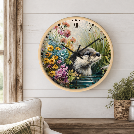 A round wall clock with a light wood frame hangs on a white shiplap wall above a wooden mantel. The clock face features a detailed illustration of an otter in water surrounded by colorful wildflowers.