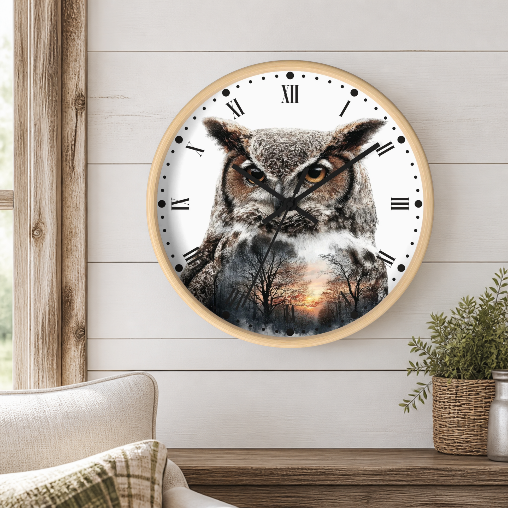 A round wall clock with a light wood frame hangs on a white shiplap wall above a wooden table. The clock face features a detailed photograph of a great horned owl with a forest sunset reflection.