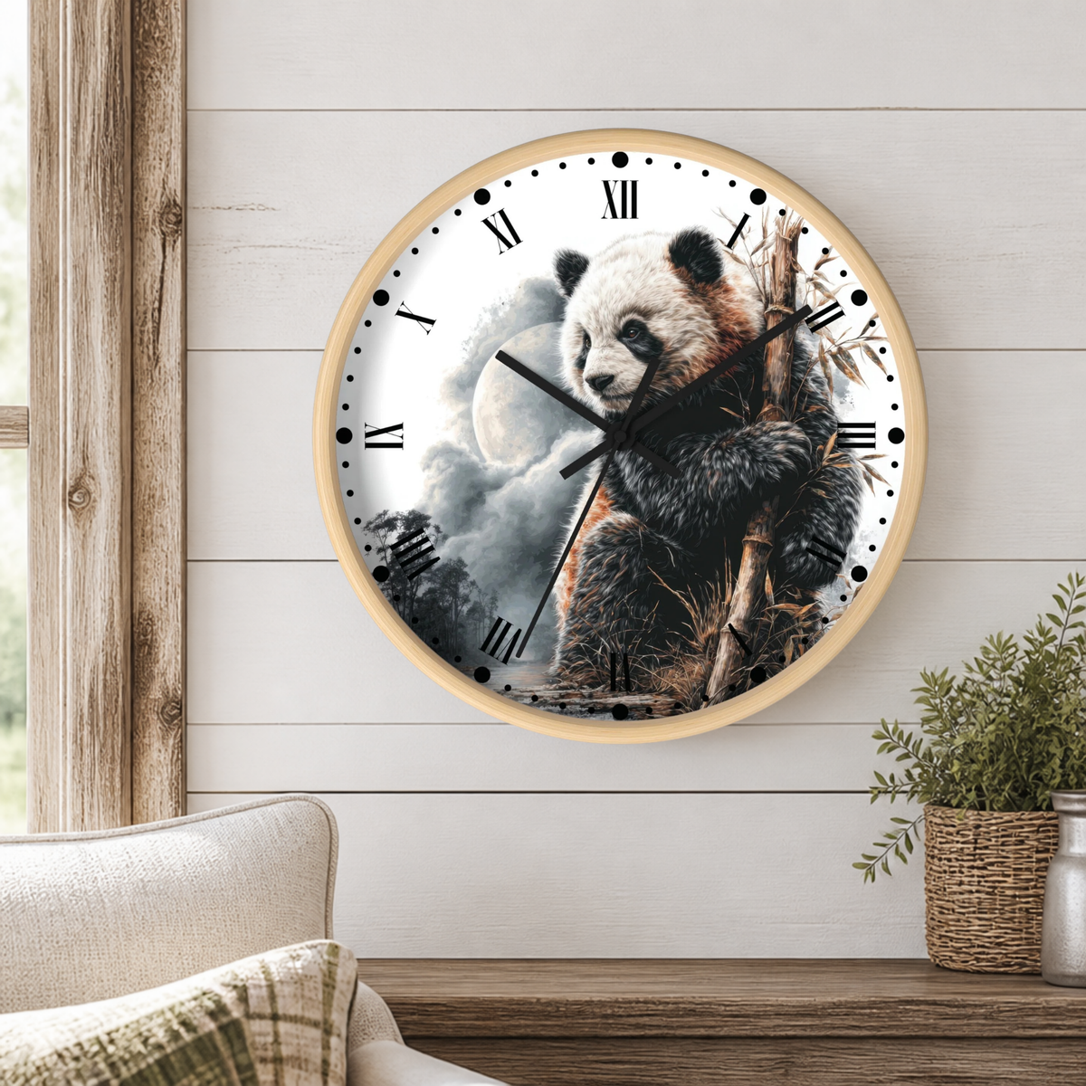 A round wall clock with a light wood frame hangs on a white shiplap wall above a wooden table. The clock face features a detailed illustration of a panda holding bamboo branches against a cloudy sky with a moon.