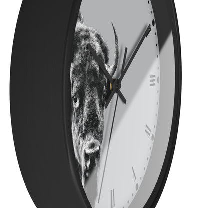 A round wall clock with a black frame and a white face featuring a black-and-white bull graphic. The clock is shown at an angle against a plain white background.