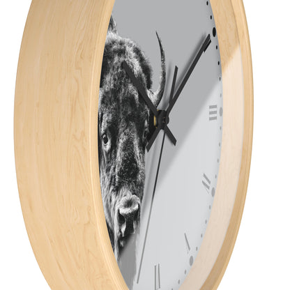 A round wall clock with a light natural wood frame and a white dial featuring a black-and-white close-up photograph of a bison. The clock has black hands and minimalist Roman numerals.