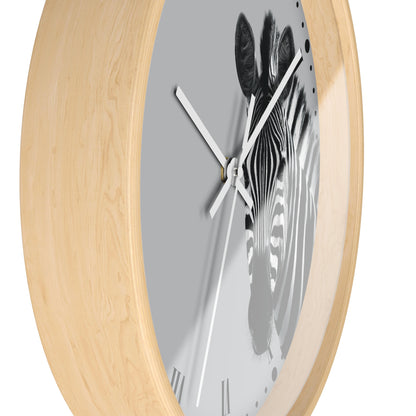 A close-up of a wall clock with a light natural wood frame and a gray dial featuring a black-and-white zebra illustration. The clock hands are white, and the background is plain white.