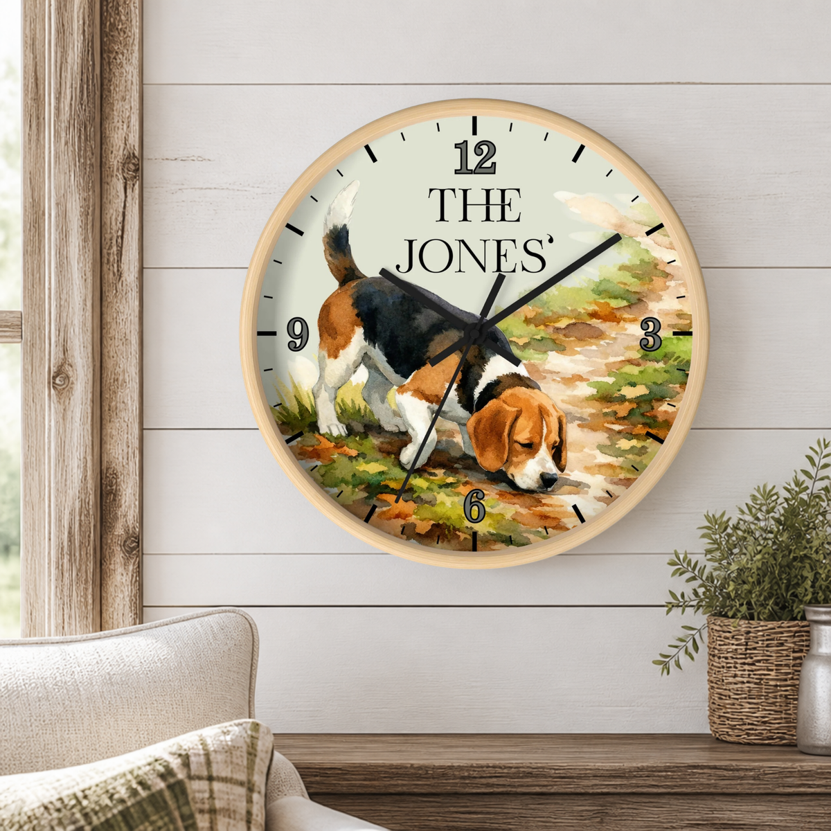 A personalized round wall clock featuring a beagle illustration and the text 'THE JONES' on the clock face, mounted on a white shiplap wall in a styled room setting.