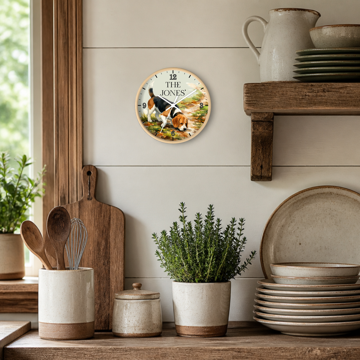 A round wall clock featuring a detailed illustration of a brown elephant, styled on a light beige shiplap wall above a rustic wooden shelf with ceramic dishes and plants.