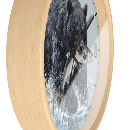 Round wall clock with a light natural wood frame and a printed design of a black bear catching a fish in the center, shown against a plain white background.