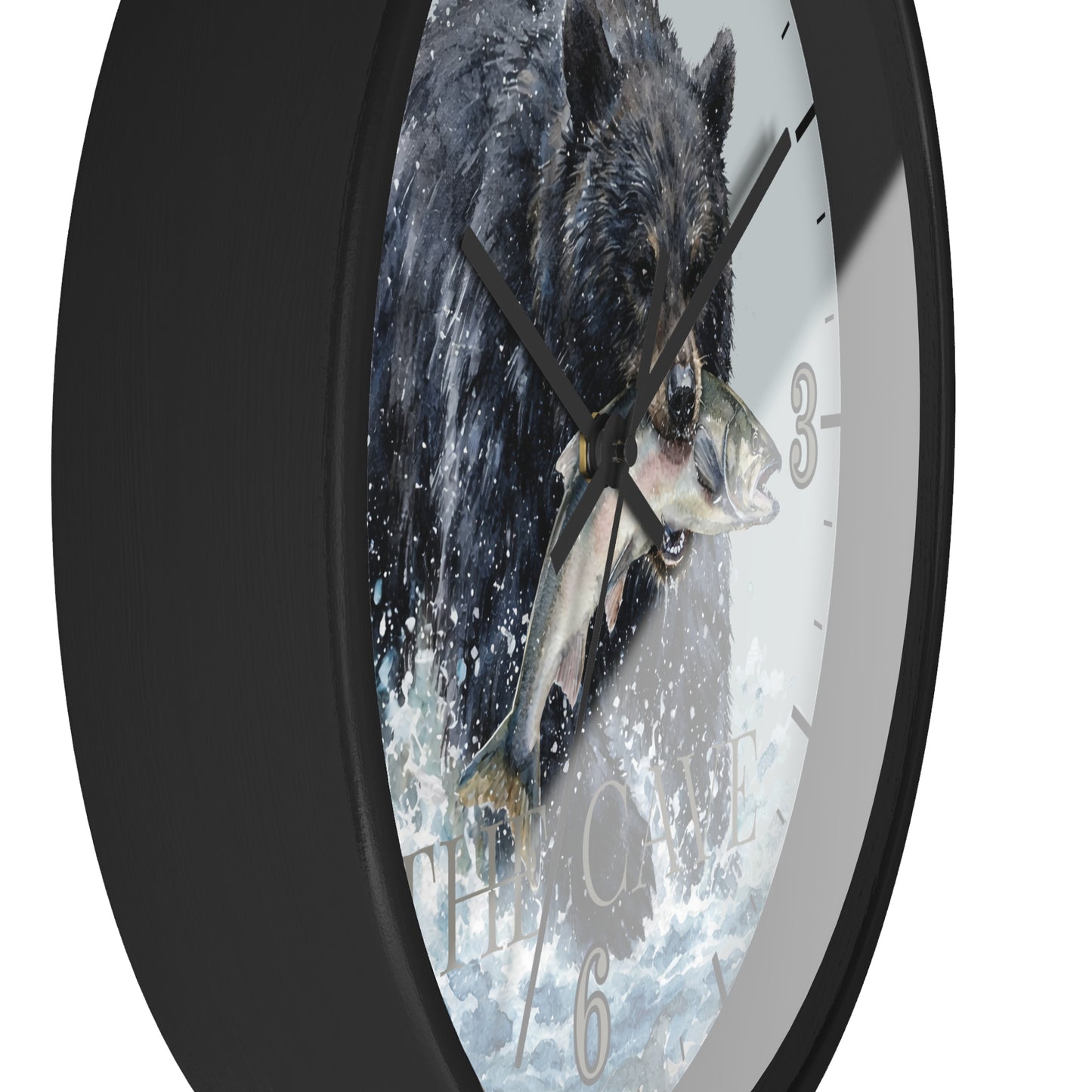 A round wall clock with a black frame and a printed face showing a black bear catching a fish in splashing water. The clock is shown at an angle against a plain white background.