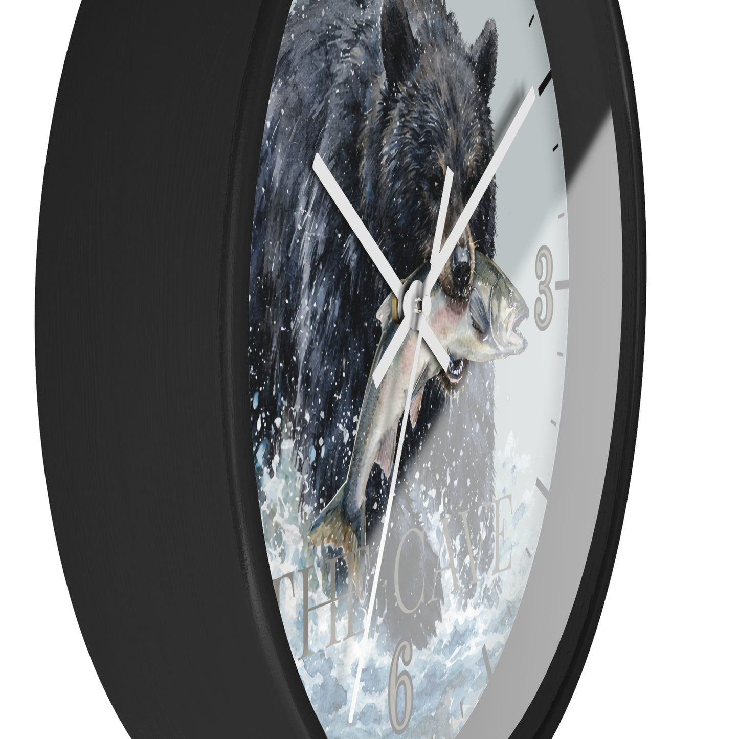 A round wall clock with a black frame and a printed face showing a black bear catching a fish in splashing water. The clock is shown at an angle against a plain white background.