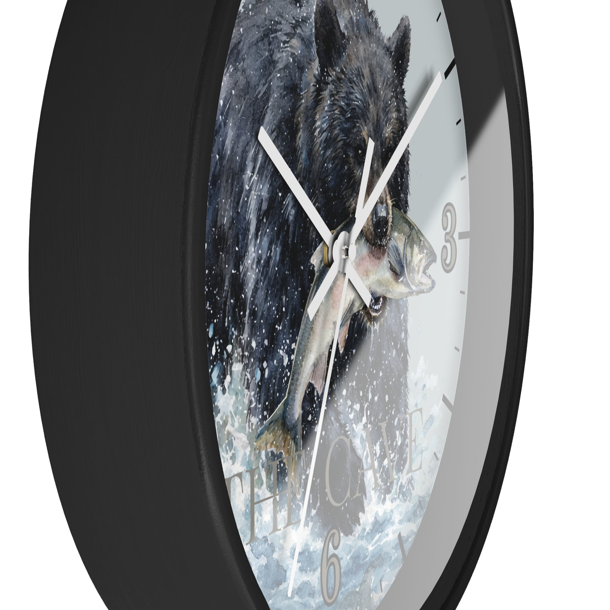 A round wall clock with a black frame and a printed face showing a black bear catching a fish in splashing water. The clock is shown at an angle against a plain white background.