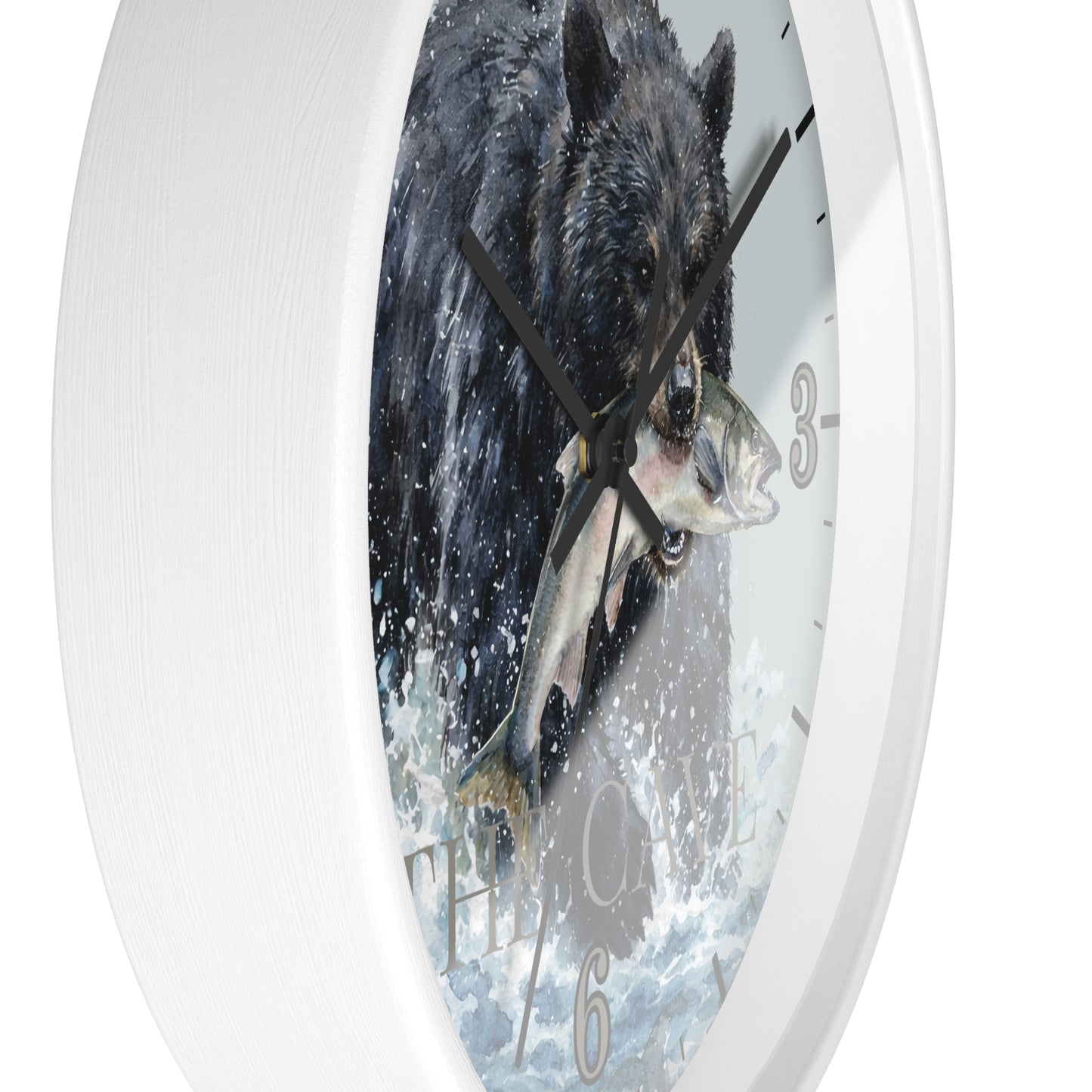 A white round wall clock featuring a printed illustration of a black bear catching a fish in splashing water, with black hands and gray Arabic numerals.
