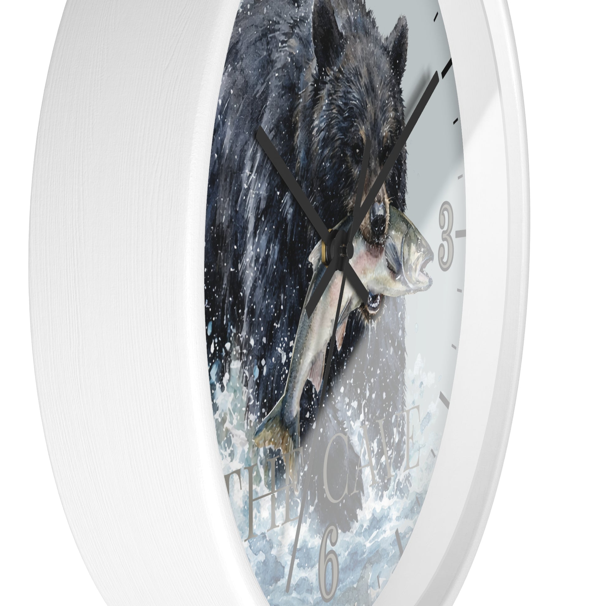 A white round wall clock featuring a printed illustration of a black bear catching a fish in splashing water, with black hands and gray Arabic numerals.