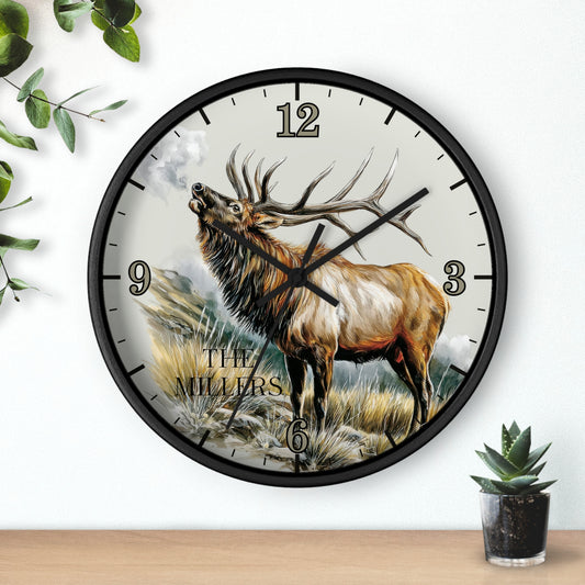 A round wall clock with a black frame and a printed illustration of a large elk standing in a grassy landscape. The clock face has black Arabic numerals and black hands, and the words 'THE MILLIERS' appear near the bottom.