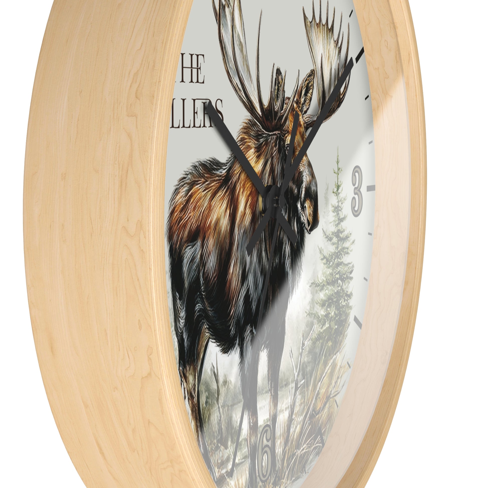 Round wall clock with a light natural wood frame and a printed face featuring a moose illustration, partial text reading 'THE MILLERS', and black clock hands.