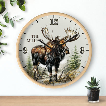 A round wall clock with a light wood frame and a nature illustration of a moose on the dial. The clock face is off-white with black Arabic numerals and the text 'THE MILLERS' near the 12.