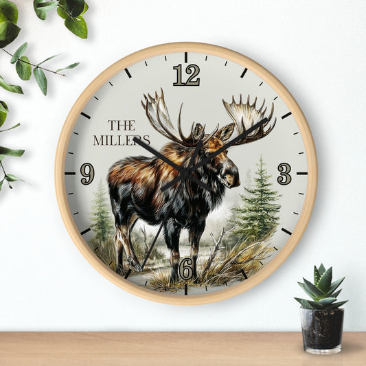A round wall clock with a light wood frame and a nature illustration of a moose on the dial. The clock face is off-white with black Arabic numerals and the text 'THE MILLERS' near the 12.