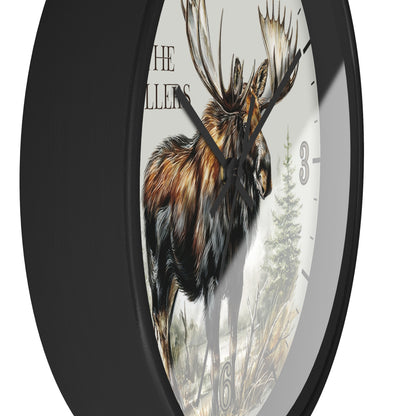 A round wall clock with a black frame and a printed moose illustration on the face, with partial text and clock numbers visible against a white background.