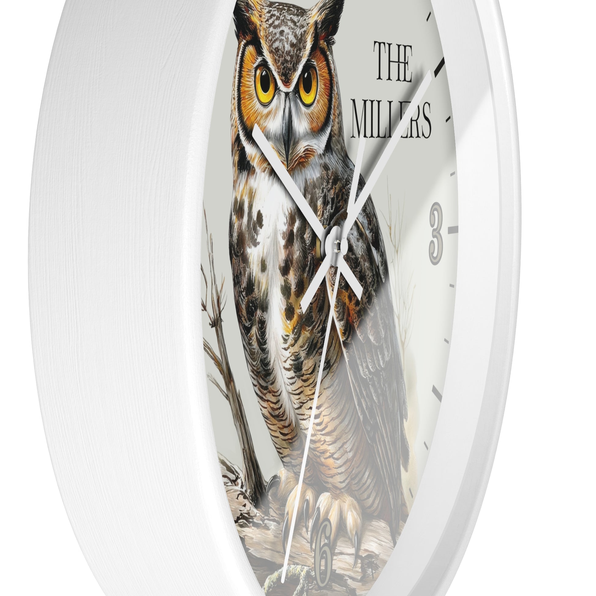 A white round wall clock featuring a detailed illustration of a great horned owl on the face, with black hands, black hour markers, and the text 'THE MILLERS' near the top right.