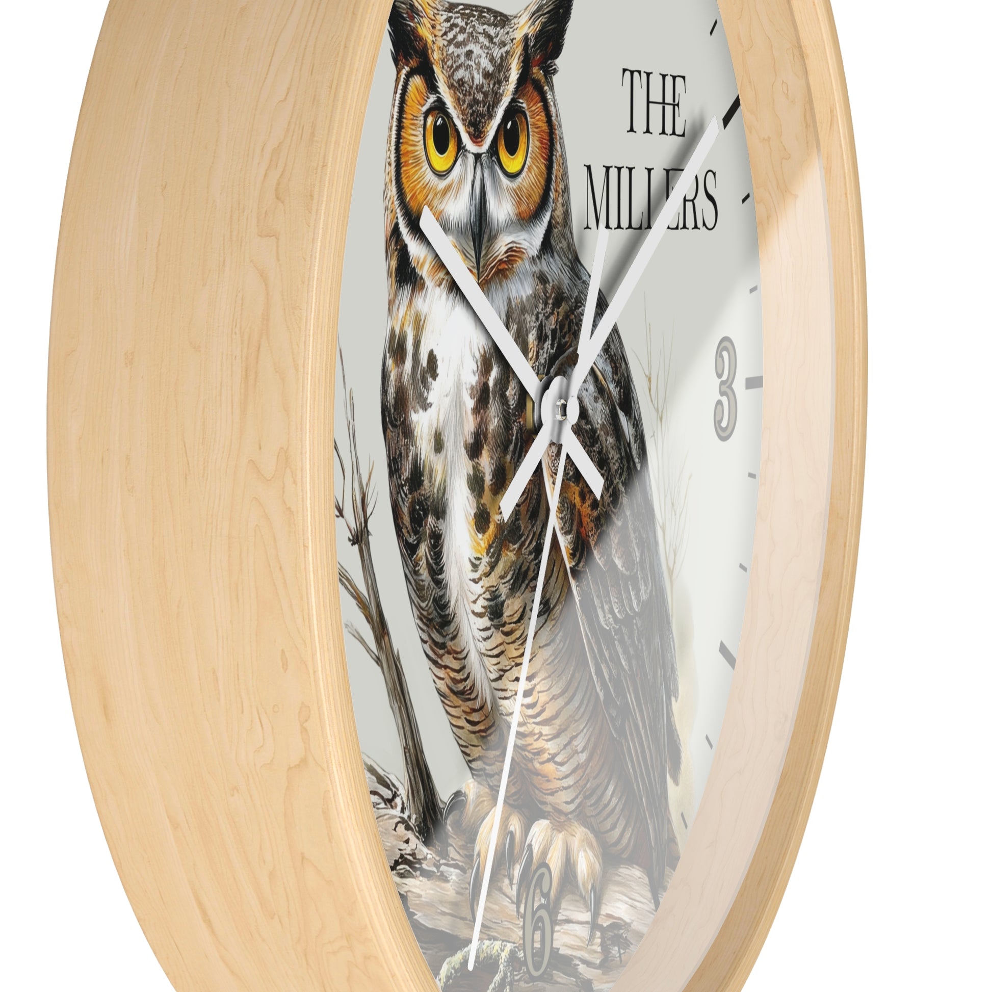 Round wall clock with a light natural wood frame and a printed owl illustration on the face. The clock includes the text 'THE MILLERS' and black numeral markers, with white hands.