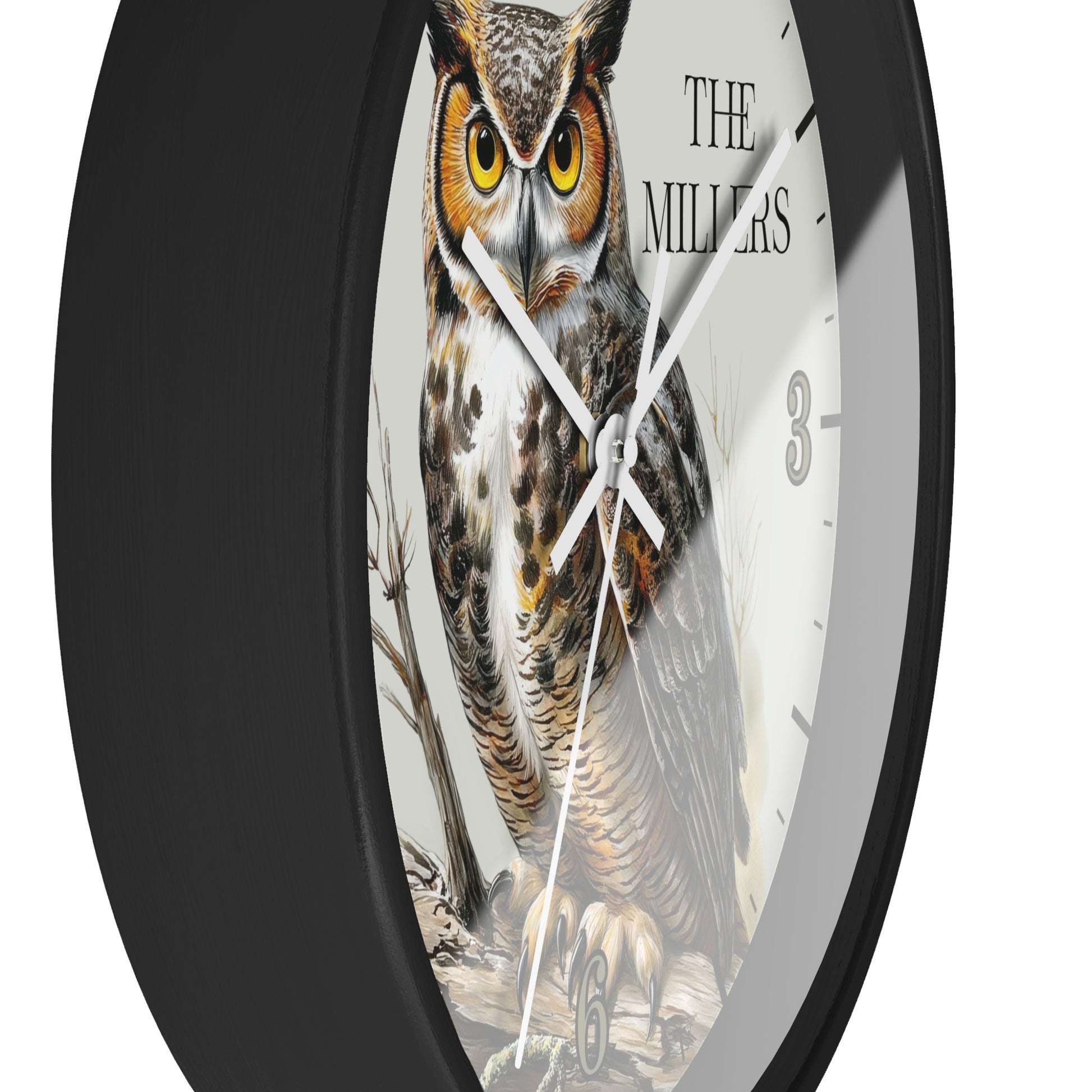 A round wall clock with a black frame and a white face featuring a detailed illustration of a great horned owl. The text 'THE MILLERS' is printed on the clock face, along with black Arabic numerals.