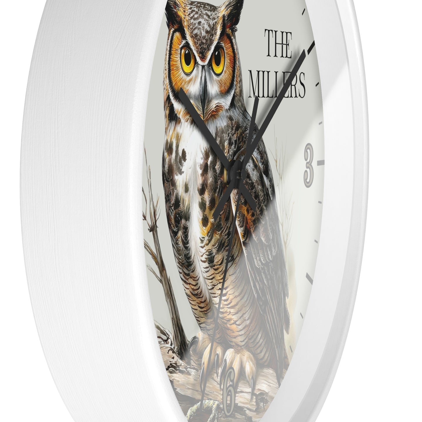 A round white wall clock featuring a detailed illustration of a great horned owl on the face, with black hands, black hour markers, and the text 'THE MILLERS' near the top right.