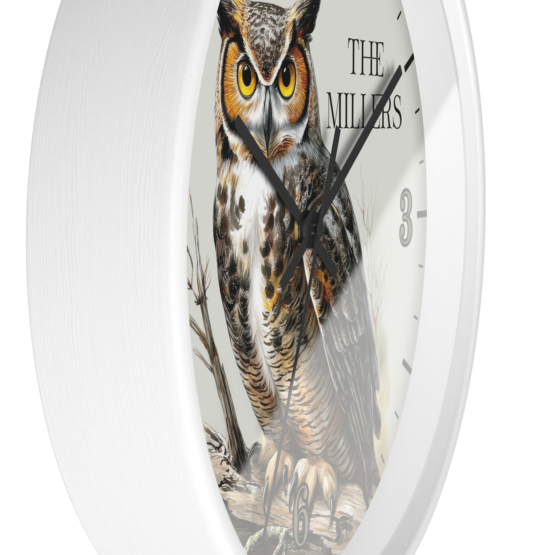 A round white wall clock featuring a detailed illustration of a great horned owl on the face, with black hands, black hour markers, and the text 'THE MILLERS' near the top right.