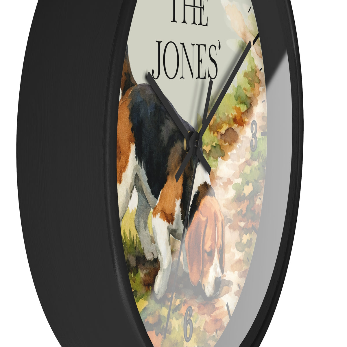 A round wall clock with a black frame and a printed watercolor-style face showing a tricolor dog on a path, with the text 'THE JONES' at the top.