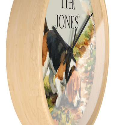 Round wall clock with a light natural wood frame and a printed dog illustration on the face. The artwork shows a black, white, and tan dog walking along a path, with the text 'THE JONES' visible near the top.