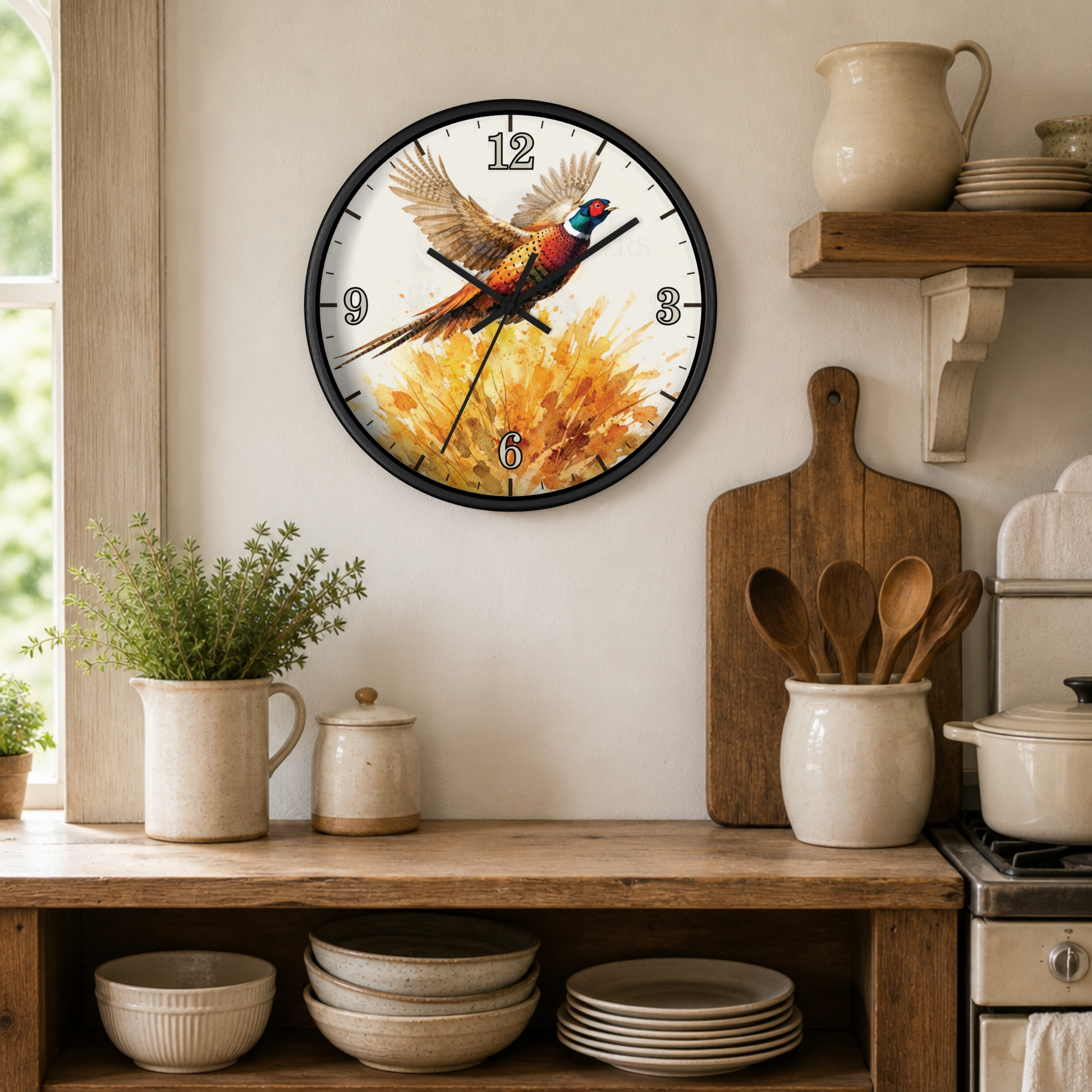 A round wall clock with a black frame hangs on a beige wall in a rustic kitchen setting. The clock face features a colorful pheasant bird perched on golden autumn leaves.
