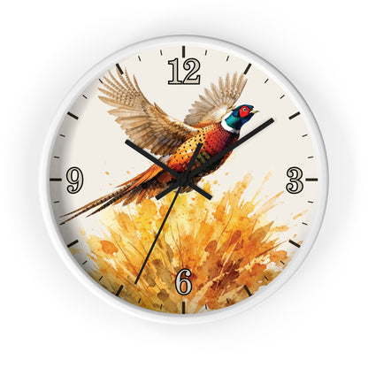 A round wall clock with a white frame and a printed design of a pheasant bird flying over a golden splash of watercolor, shown on a plain white background.