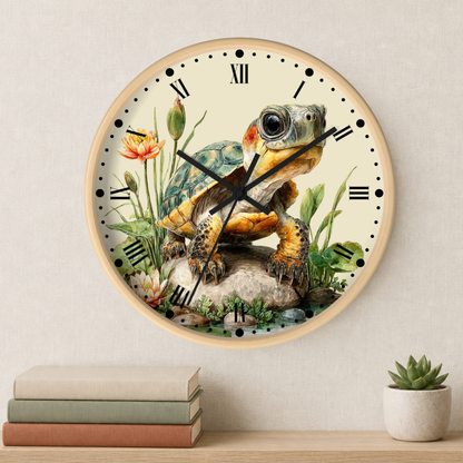 A round wall clock with a light wood frame and a detailed illustration of a tortoise sitting on rocks among flowers, mounted on a beige wall above a shelf with books and a small succulent.