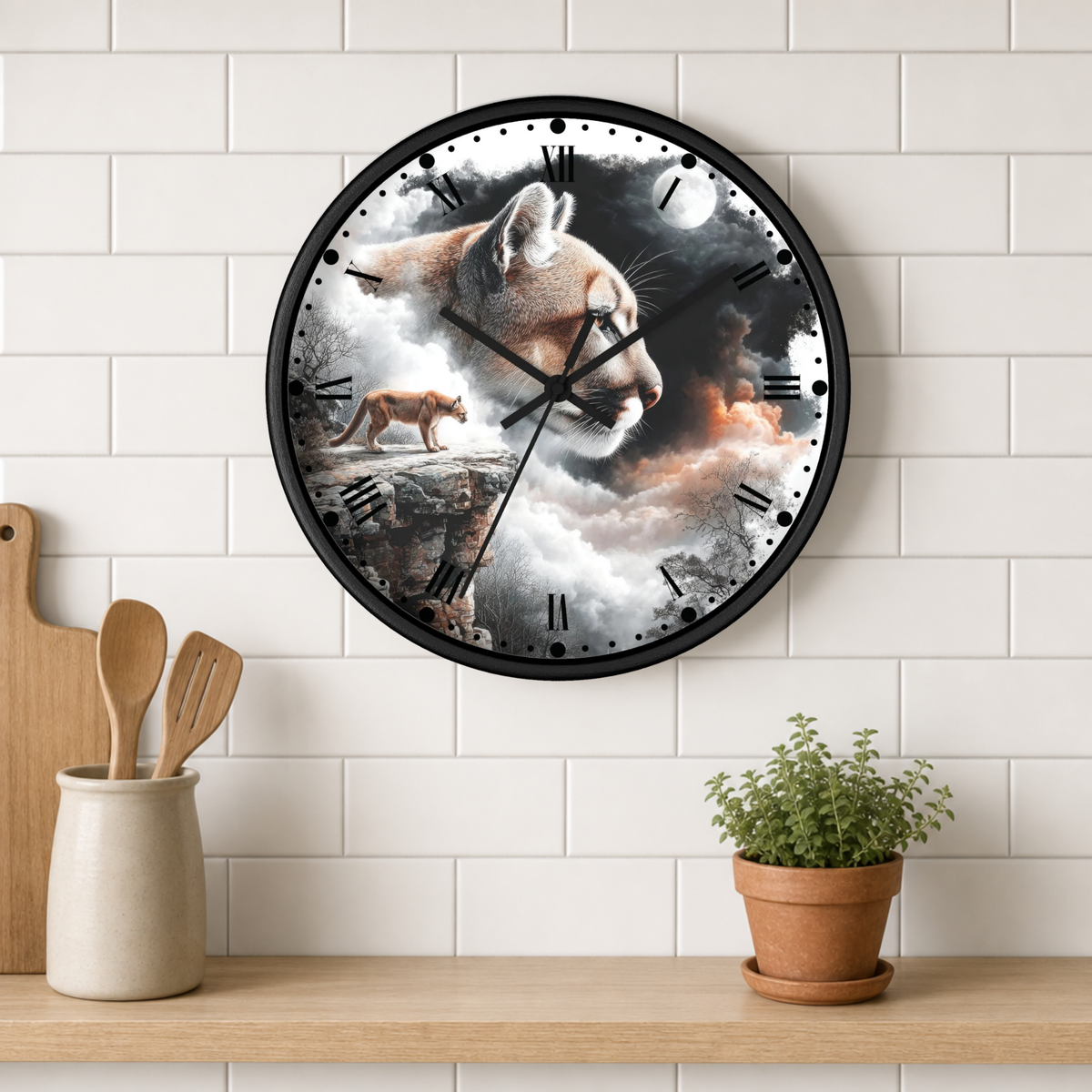 A round wall clock with a black frame and a surreal animal print featuring a large cat and a fox in clouds, mounted on a white subway tile wall above a wooden shelf with kitchen utensils and a potted plant.