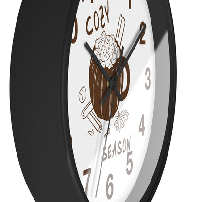 A close-up of a round wall clock with a black frame and a white face featuring a brown mug illustration, brown numerals, and black hands.