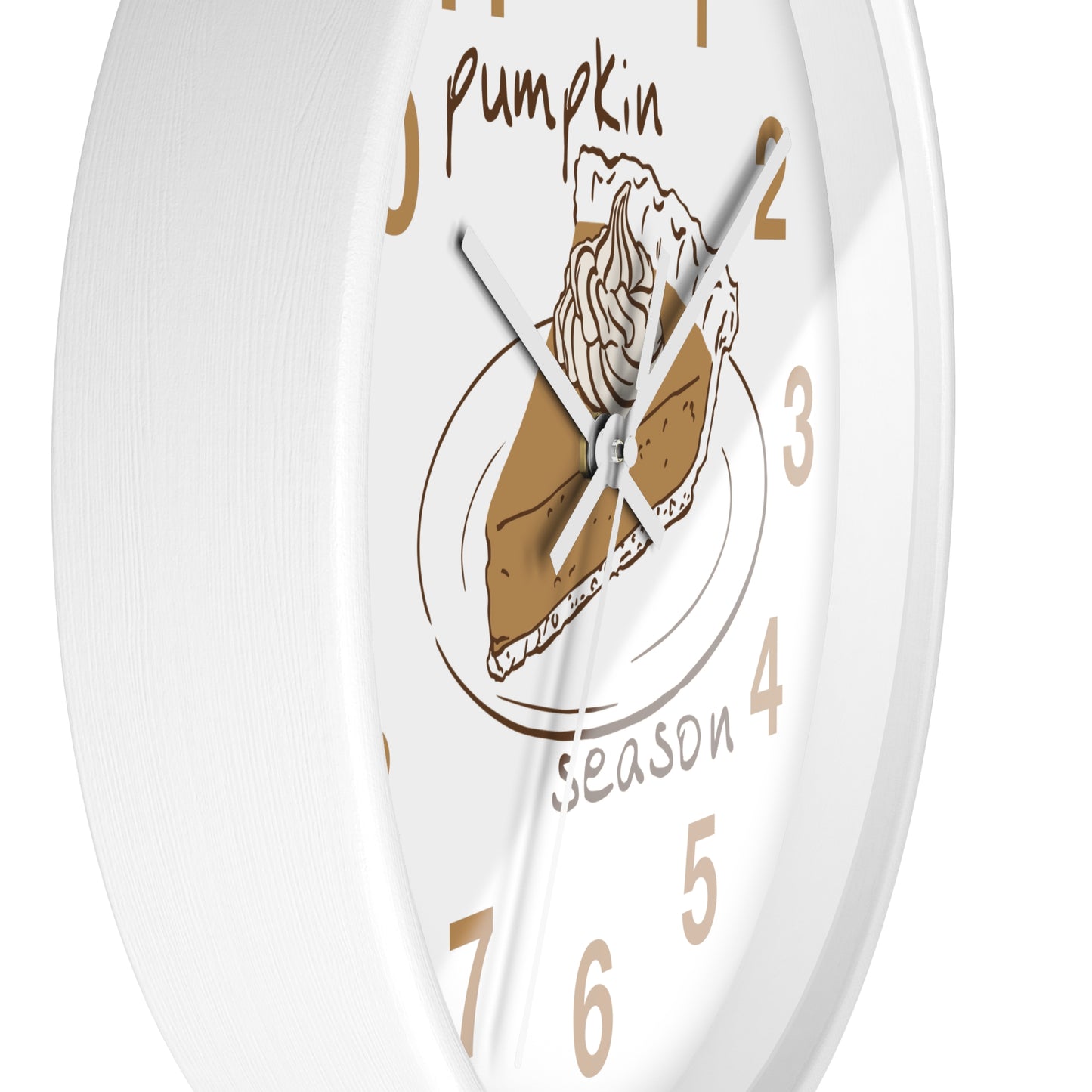 A white round wall clock with a pumpkin pie illustration at the center and tan numerals, including the words 'Pumpkin' and 'season' on the face.