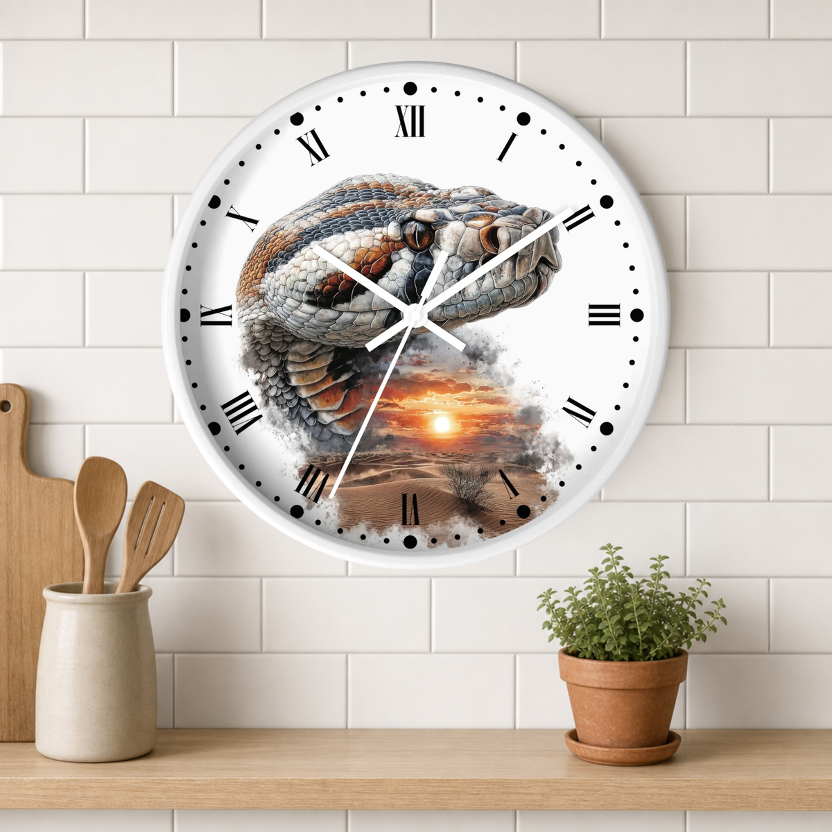 A round wall clock with a white face and Roman numerals, featuring a detailed illustration of a coiled snake over a sunset landscape. The clock is mounted on a white subway tile wall above a wooden shelf with a small potted plant and wooden utensils.