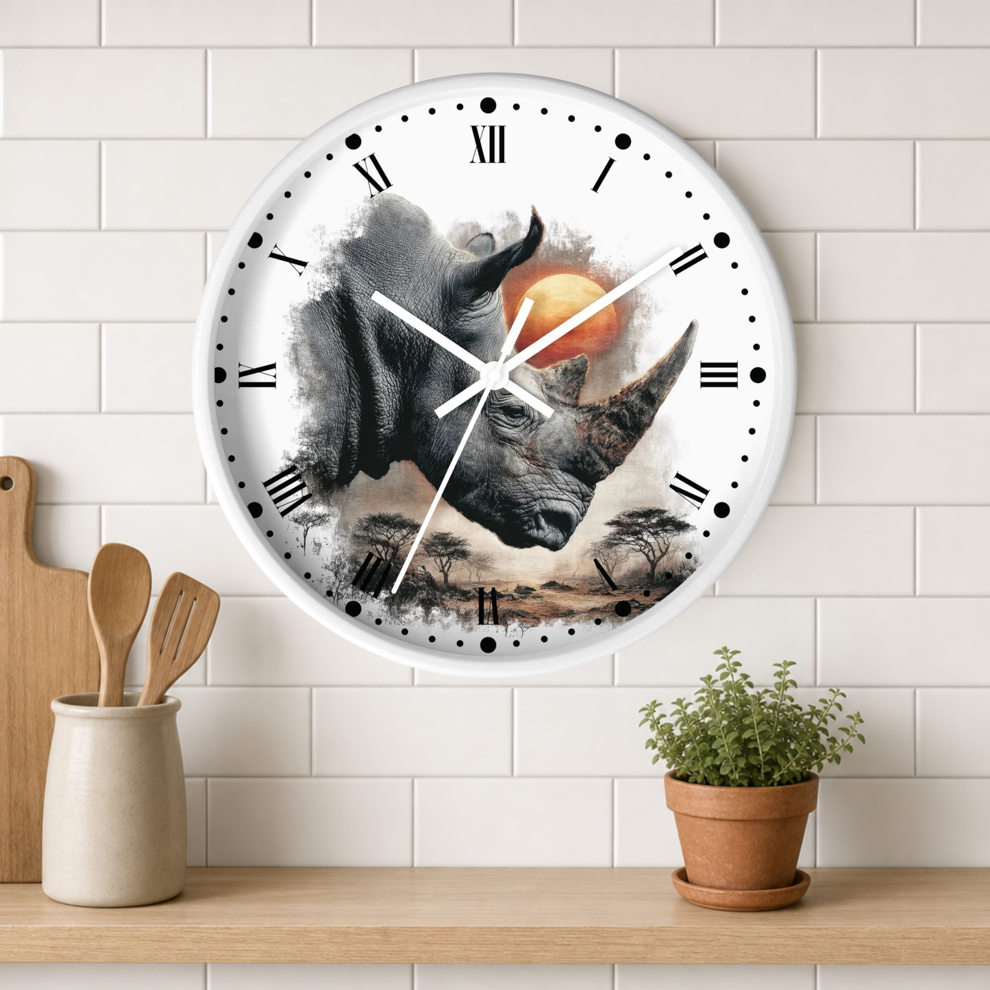 A round wall clock with a white frame and a printed rhinoceros illustration on the face, mounted on a white subway-tile wall above a wooden shelf with a small potted plant and utensils.