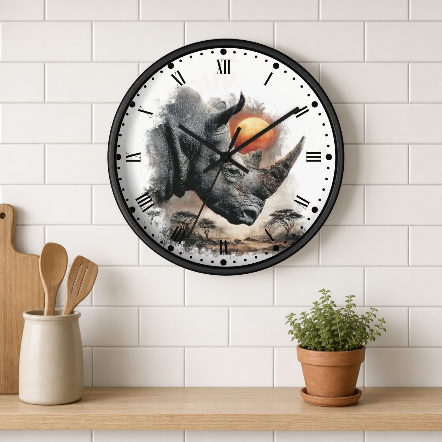 A round wall clock with a black frame and a rhinoceros illustration on the face, mounted on a white subway tile wall above a wooden shelf with kitchen utensils and a potted plant.
