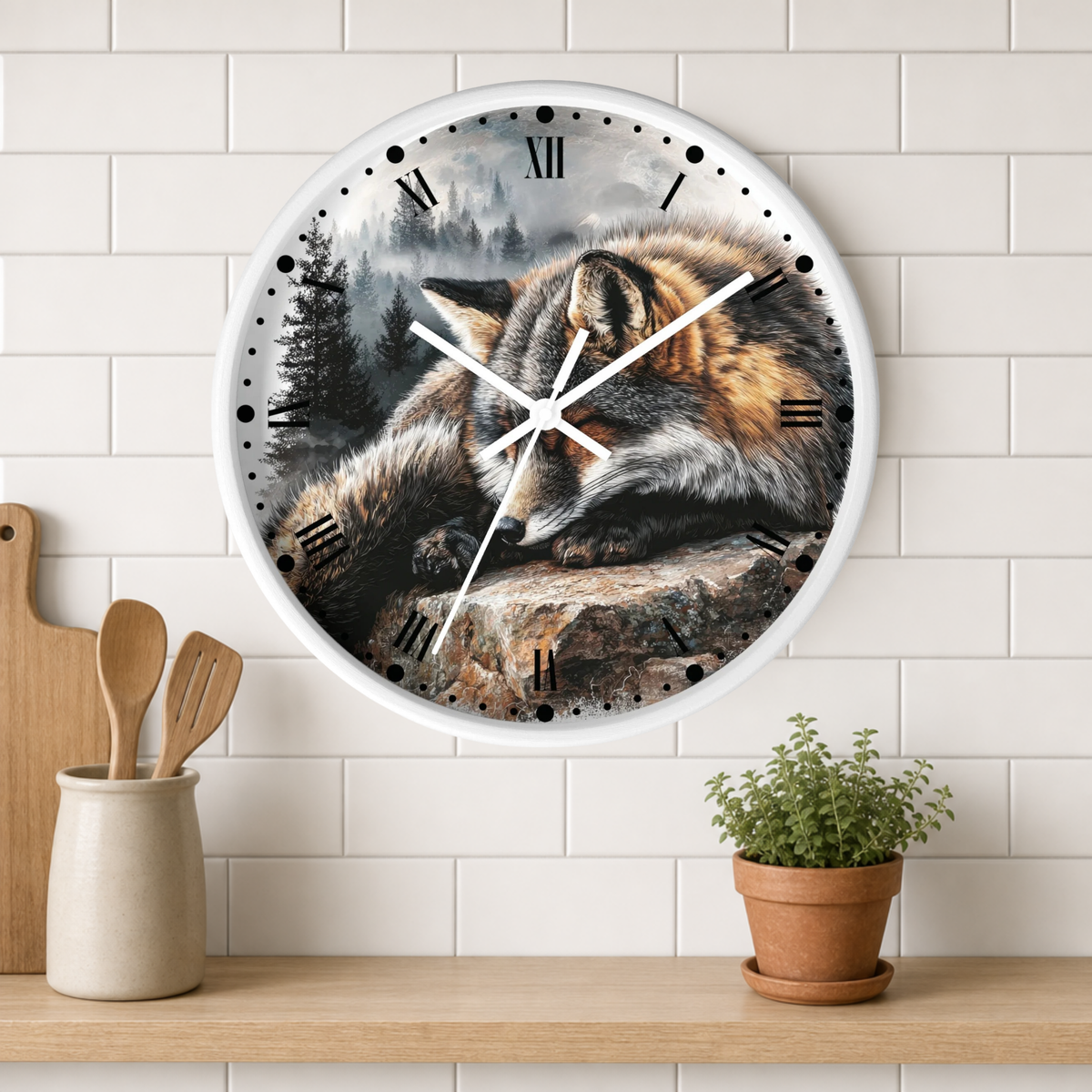 A round wall clock with a realistic fox resting on a rock in a misty forest scene, mounted on a white subway tile wall above a wooden shelf with kitchen utensils and a potted plant.