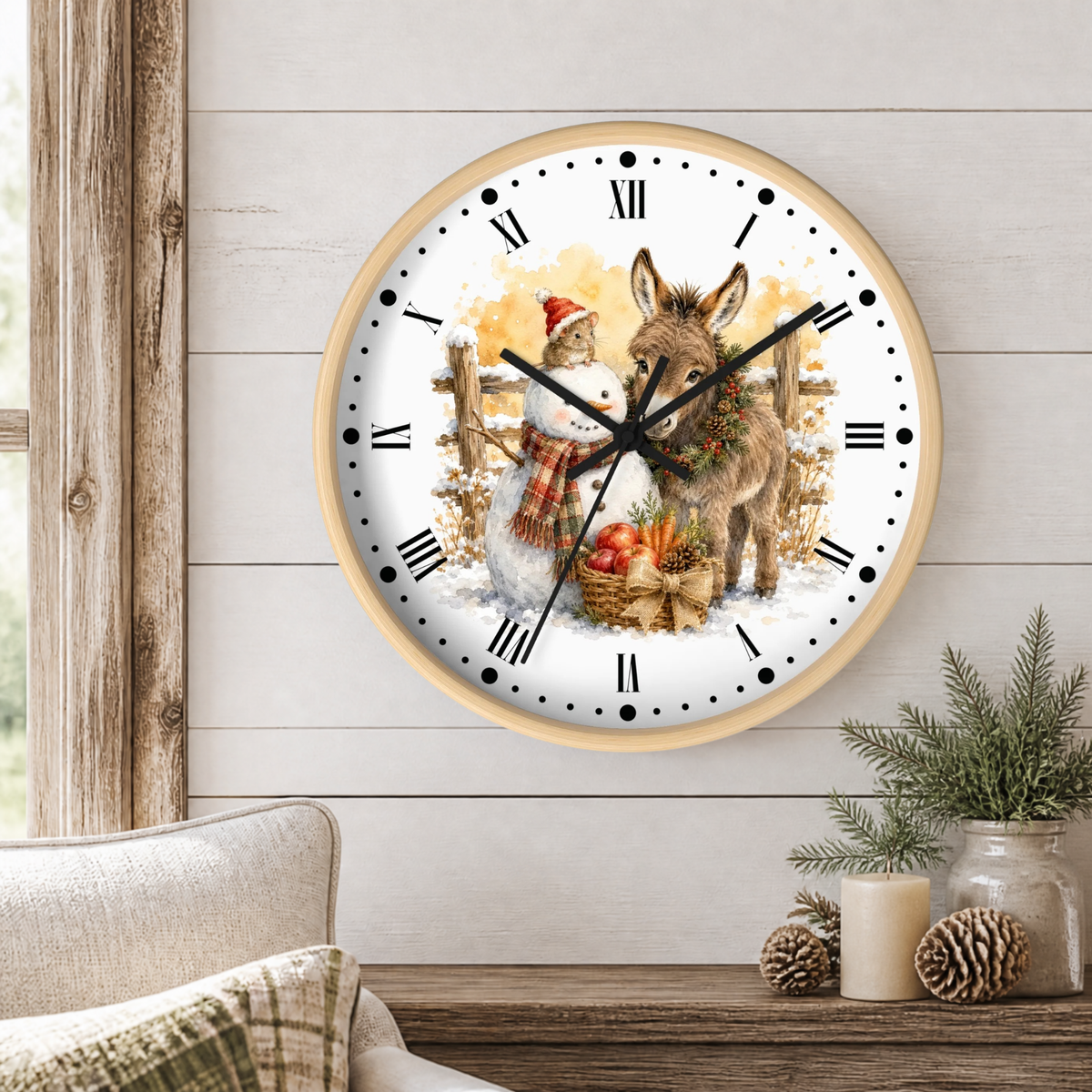A round wall clock with a light wood frame hangs on a white shiplap wall above a rustic wooden table. The clock face features a festive illustration of a snowman in a Santa hat and scarf next to a donkey with a wreath, with Roman numerals as hour markers.