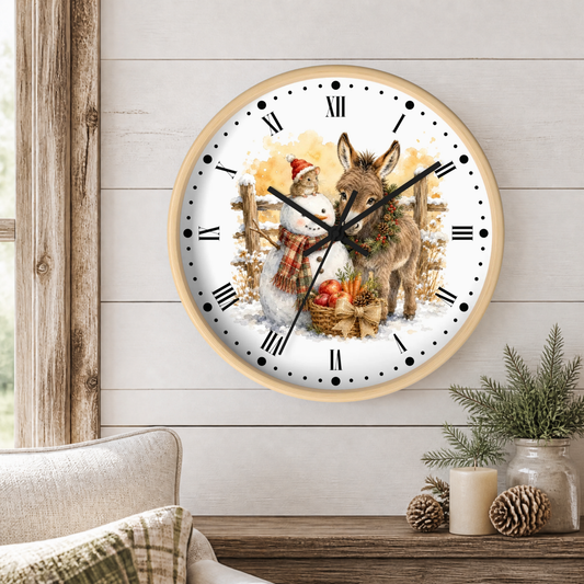 A round wall clock with a light wood frame hangs on a white shiplap wall above a rustic wooden table. The clock face features a festive illustration of a snowman in a Santa hat and scarf next to a donkey with a wreath, with Roman numerals as hour markers.