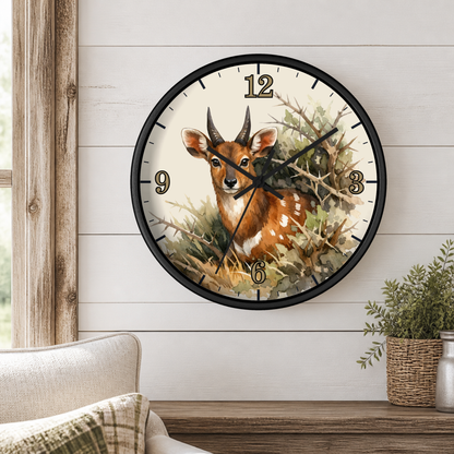A round wall clock with a black frame and a deer illustration on the face, mounted on a white shiplap wall above a wooden mantel with a small plant and part of a sofa visible.