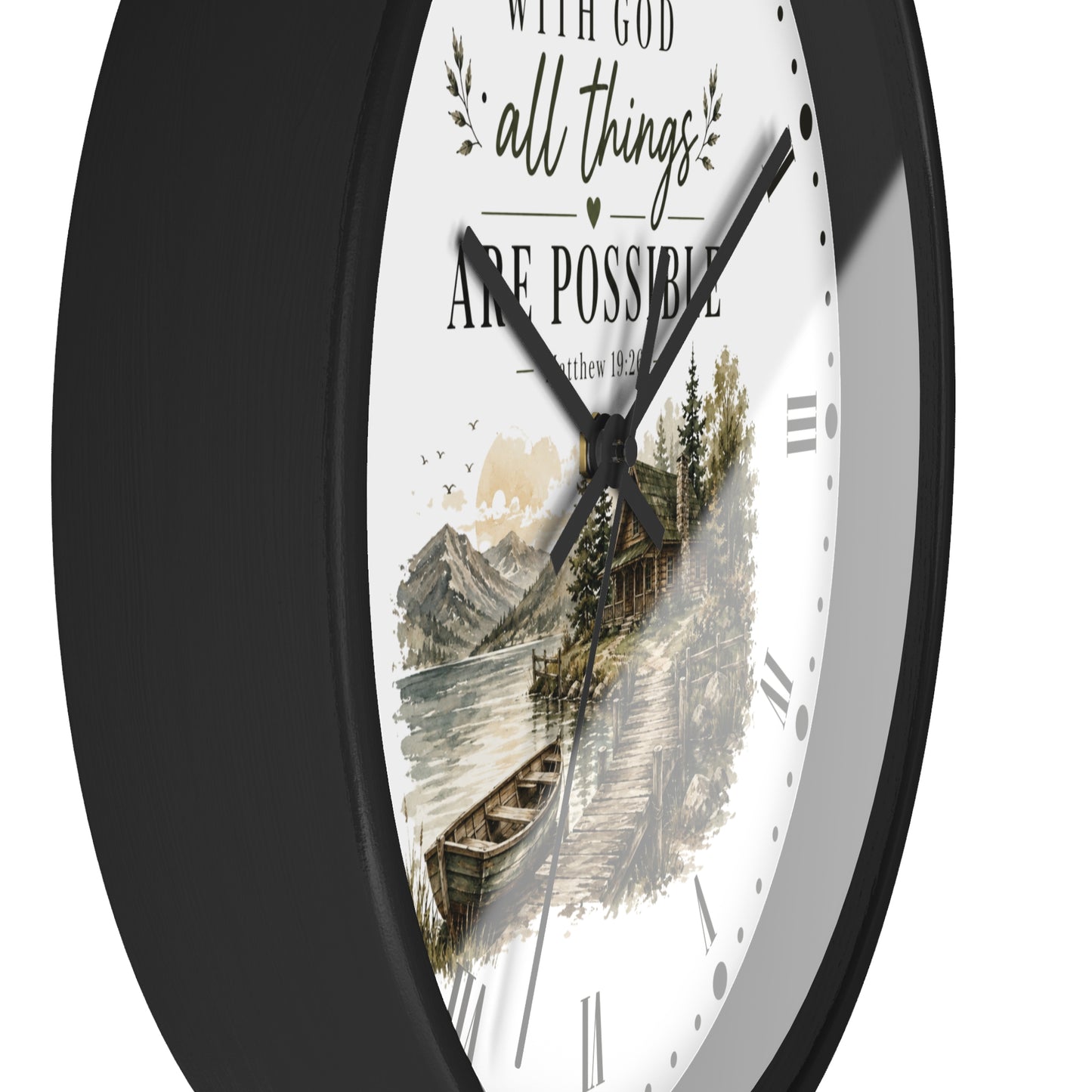 A close-up of a round wall clock with a black frame and a white dial featuring the inspirational quote 'WITH GOD all things ARE POSSIBLE' above a scenic illustration of a lake, cabin, and mountains.