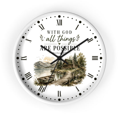 A round white wall clock with black Roman numerals and hands, featuring a scenic lake cabin illustration and the text 'WITH GOD all things ARE POSSIBLE Matthew 12:28' on the clock face.
