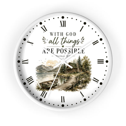 A round white wall clock with black Roman numerals and hands, featuring the inspirational quote 'WITH GOD all things ARE POSSIBLE Matthew 19:26' above a scenic illustration of a lakeside cabin and mountains.
