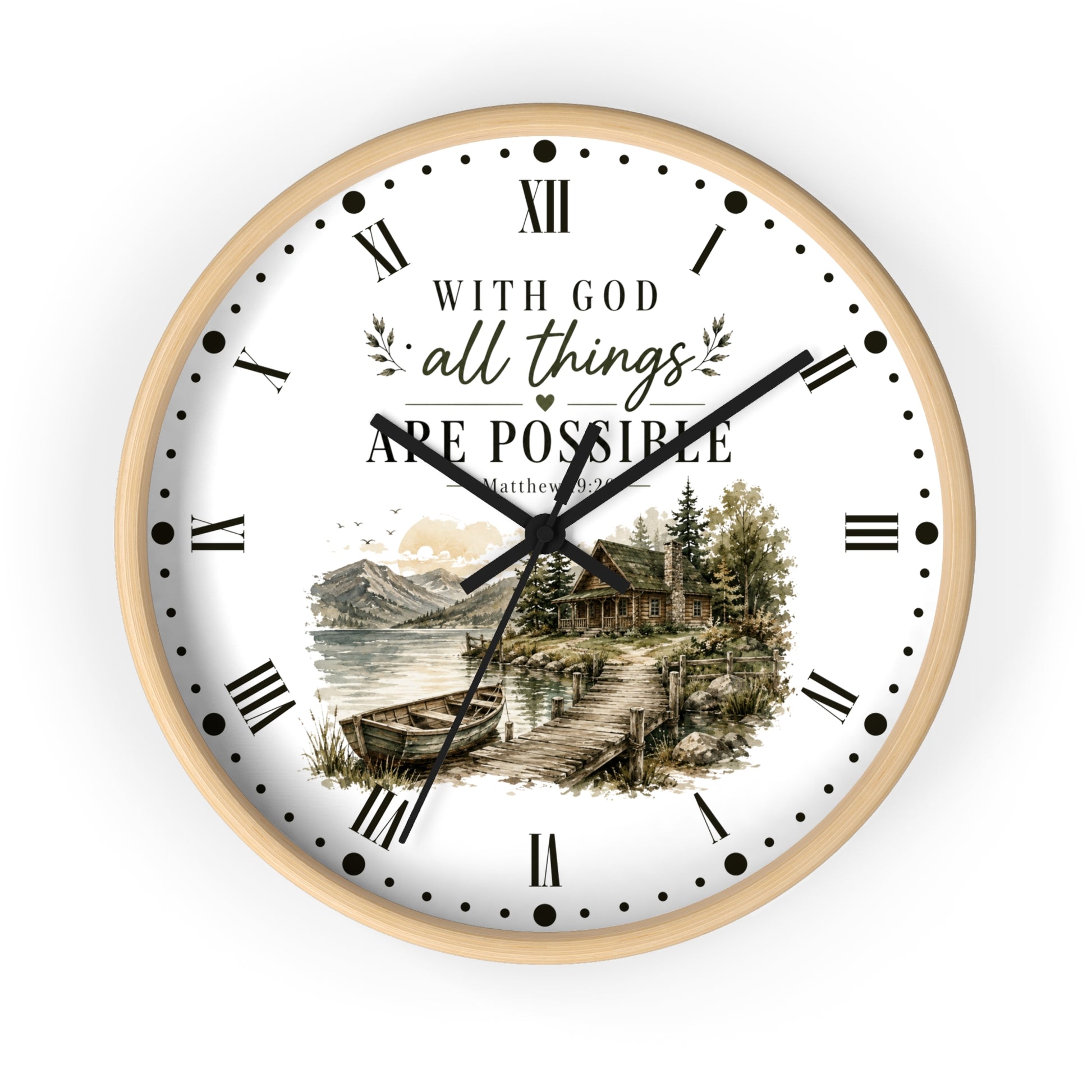 A round wall clock with a light wood frame and a white face. The clock face features black Roman numerals, black hands, and a scenic illustration of a lakeside cabin with mountains and trees.