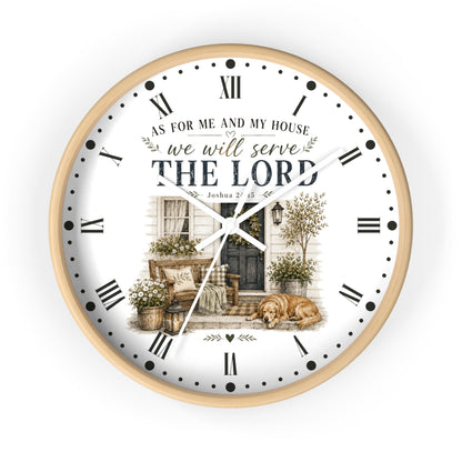 A round wall clock with a light wood frame and a white face featuring a vintage-style illustration of a porch, potted plants, and a dog. The clock face includes black Roman numerals, black hands, and the text 'AS FOR ME AND MY HOUSE we will serve THE LORD' with a Bible verse below.