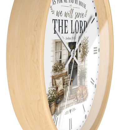 Round wall clock with a light natural wood frame and a white face featuring a rustic house illustration and the text 'AS FOR ME AND MY HOUSE we will serve THE LORD'.
