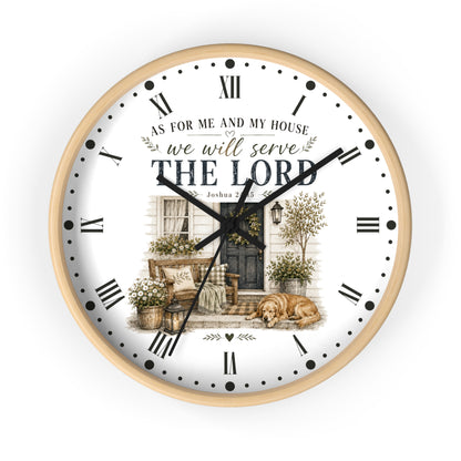 A round wall clock with a light wood frame and a white face featuring a vintage-style illustration of a porch, Roman numerals, black hands, and the text 'AS FOR ME AND MY HOUSE we will serve THE LORD'.